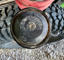 Load image into Gallery viewer, Close-up of a shock cap on a tire with a gravel surface in the background.